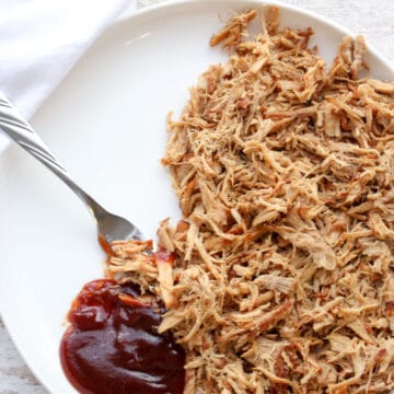 Pulled pork on a white plate with a dollop of BBQ sauce