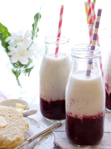 BANANA BERRY YOGURT SMOOTHIE WITH BISCUITS AND BUTTER AND FLOWERS IN THE BACKGROUND