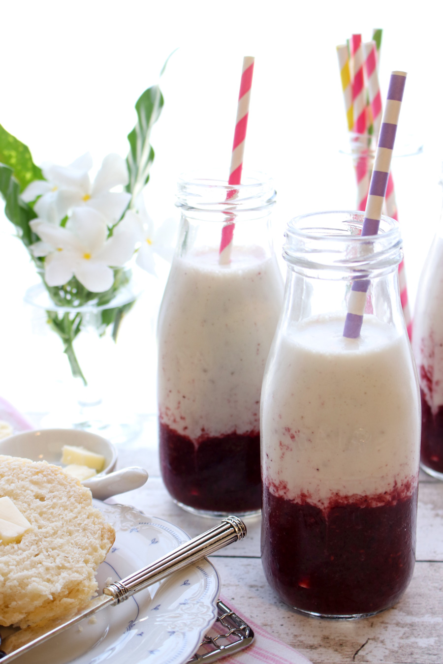 BANANA BERRY YOGURT SMOOTHIE WITH BISCUITS AND BUTTER AND FLOWERS IN THE BACKGROUND