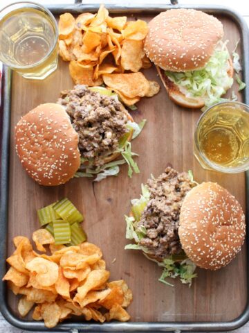 Overhead shot of sloppy joe sandwiches with chips and beer on a try