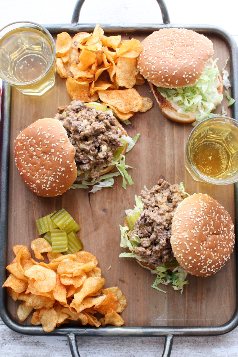 Overhead shot of sloppy joe sandwiches with chips and beer on a try