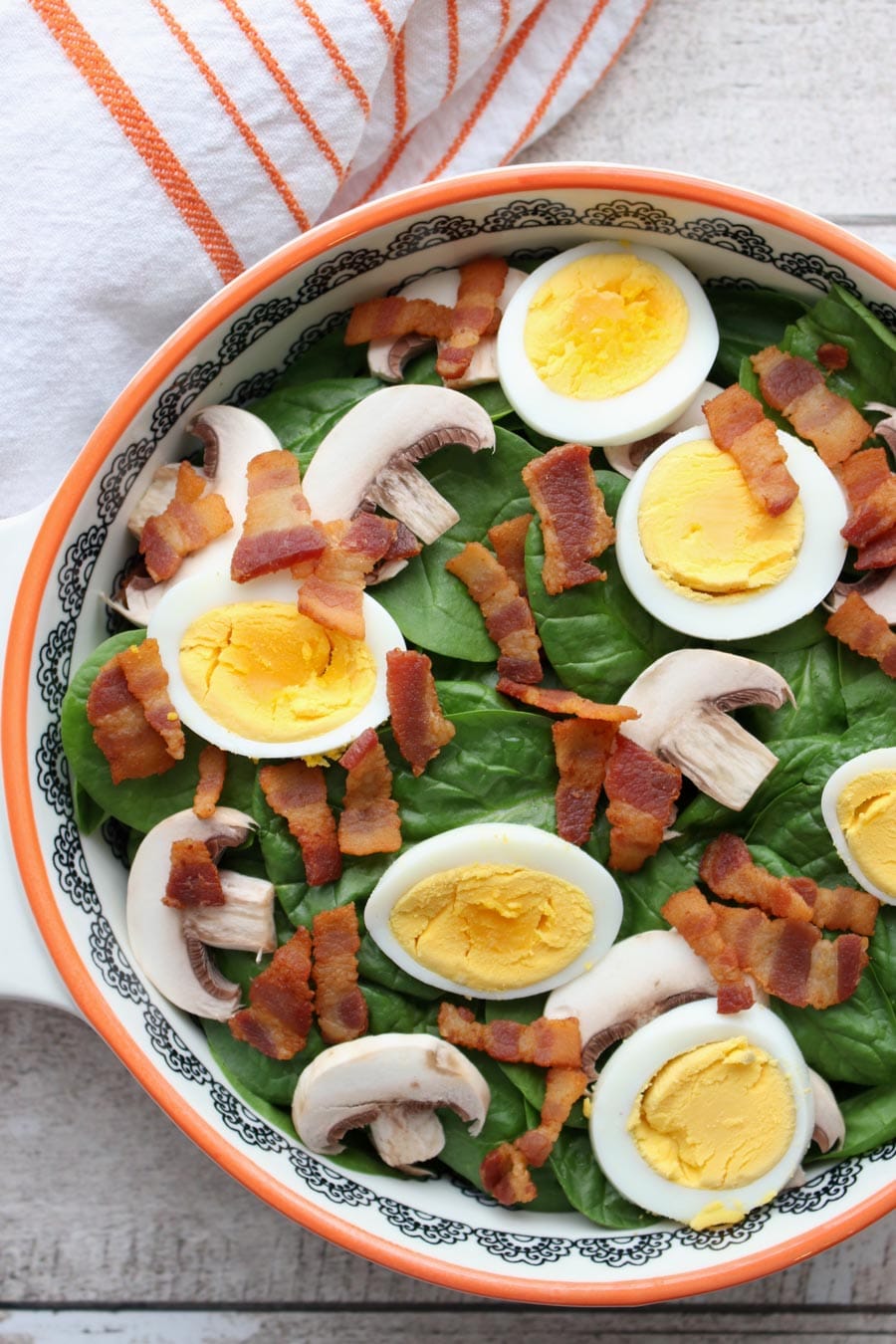 Bowl of spinach with mushrooms, eggs, bacon