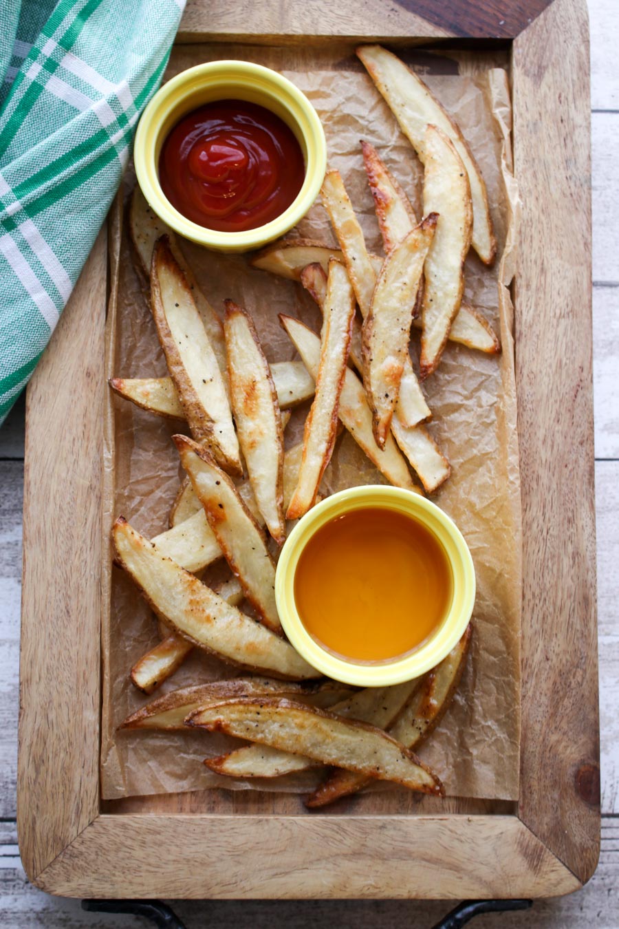 Salt and vinegar fries on a wooden tray with ketchup and vinegar