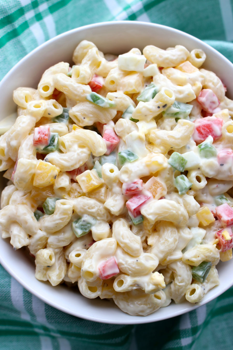 Bowl of macaroni salad sitting on a green and white cloth