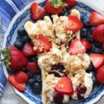 A blue bowl with two bananas filled with yogurt, topped with fruit and granola