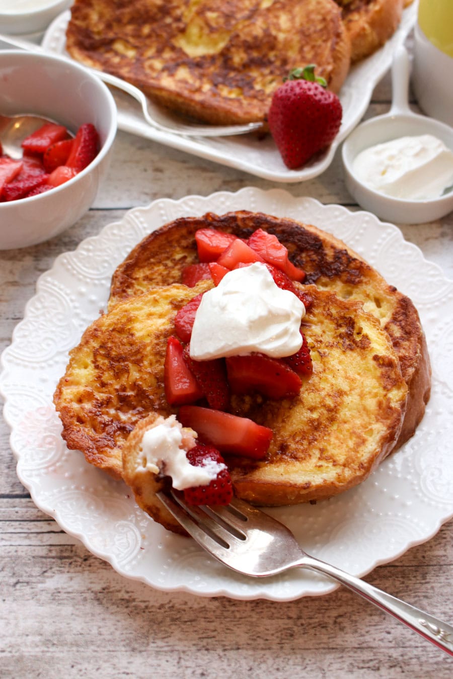 Slice of french toast on a plate with strawberries and cream