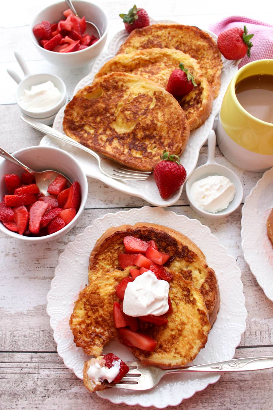 Platter and plates of french toast with strawberries and sour cream