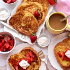 Platter and plates of french toast with strawberries and cream