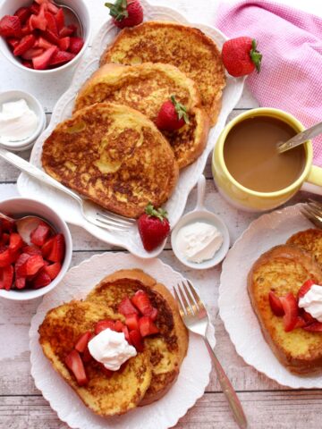 Platter and plates of french toast with strawberries and cream