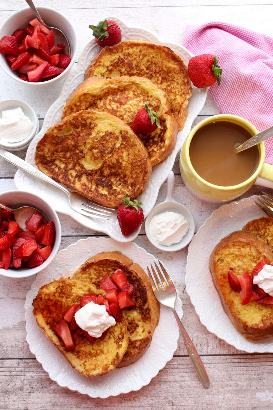 Platter and plates of french toast with strawberries and cream