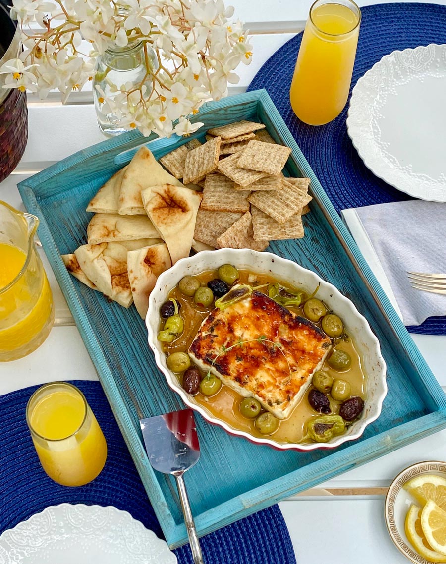 Baked Feta Cheese on a blue tray with crackers and pita bread