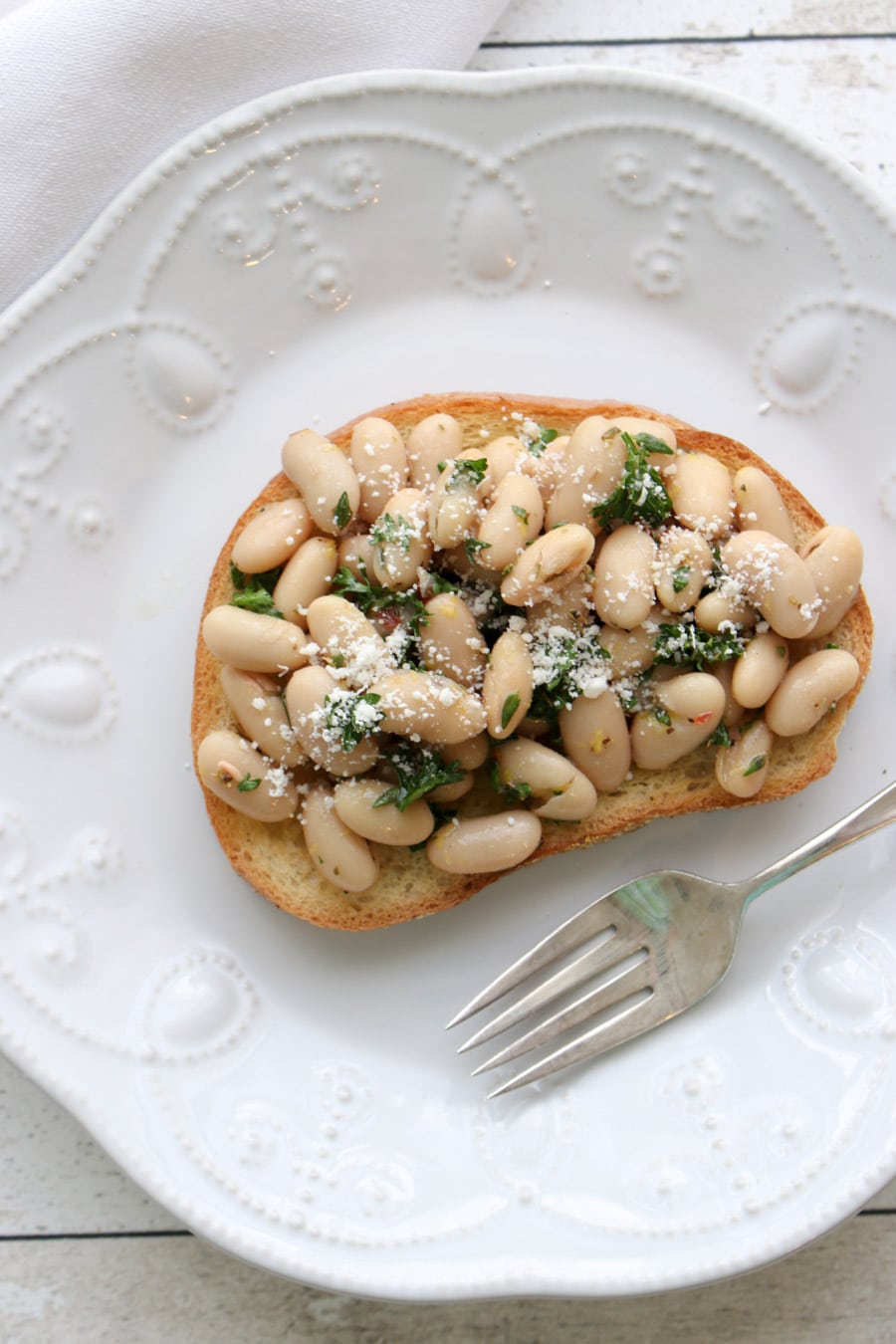 White Bean Salad piled high on a piece of toast on a plate