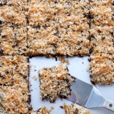 Sheet pan of Caramel Coconut Samoa Brownies with a spatula scooping one brownie