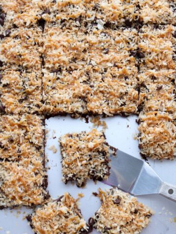 Sheet pan of Caramel Coconut Samoa Brownies with a spatula scooping one brownie