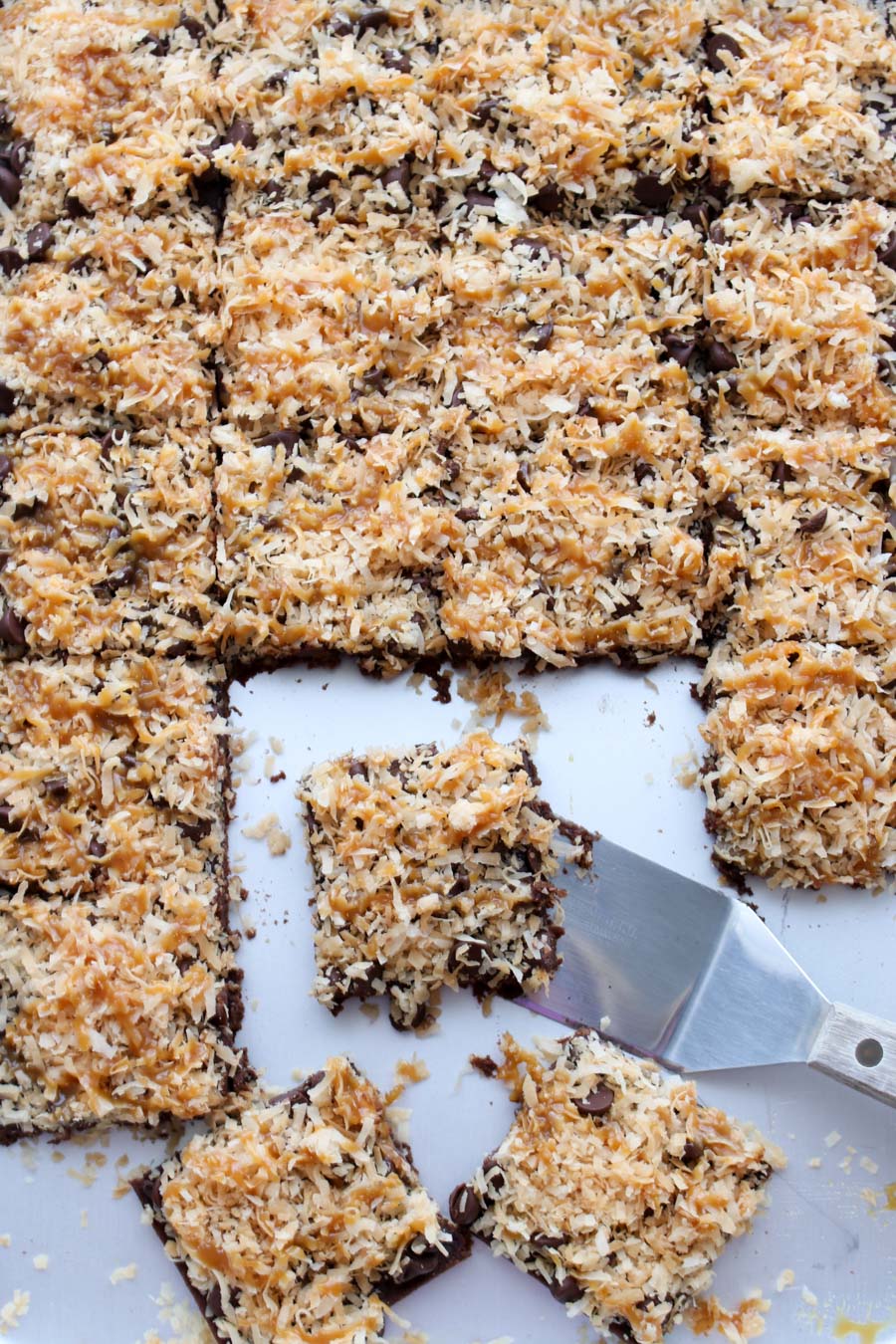 Sheet pan of Caramel Coconut Samoa Brownies with a spatula scooping one brownie