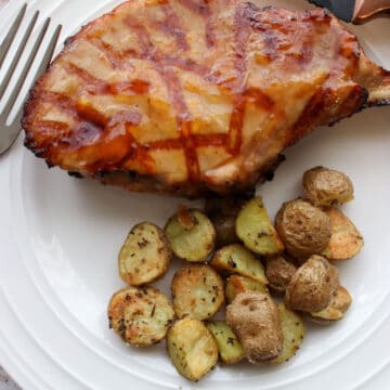 1 pork chop and roasted potatoes on a white plate