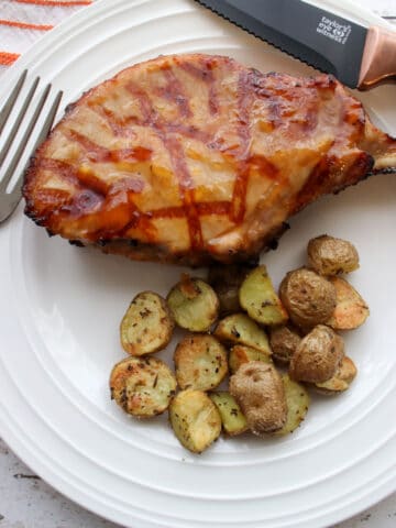 1 pork chop and roasted potatoes on a white plate