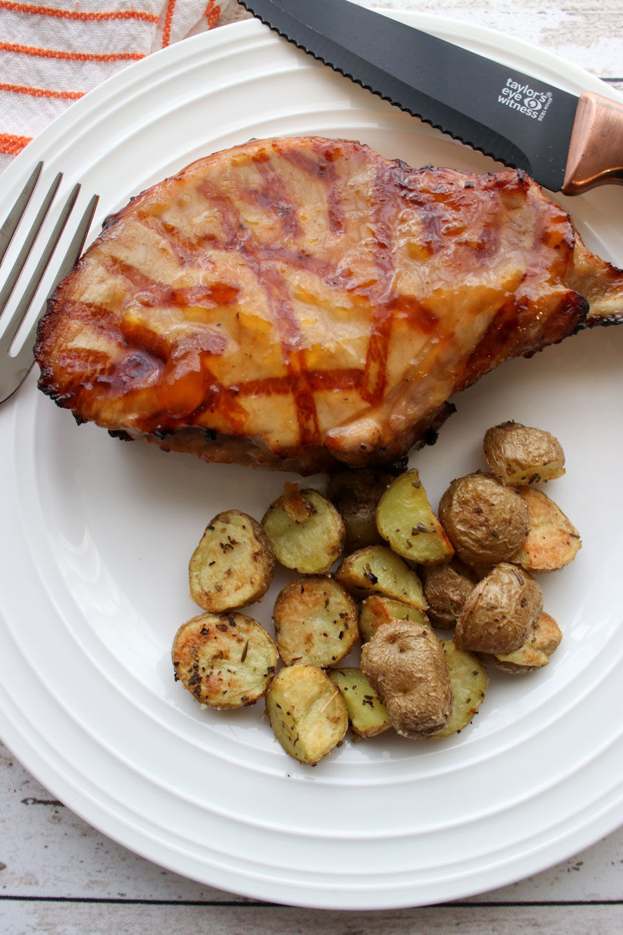 1 pork chop and roasted potatoes on a white plate