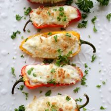 Four Stuffed Mini Peppers on a white plate topped with fresh parsley