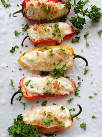 Four Stuffed Mini Peppers on a white plate topped with fresh parsley