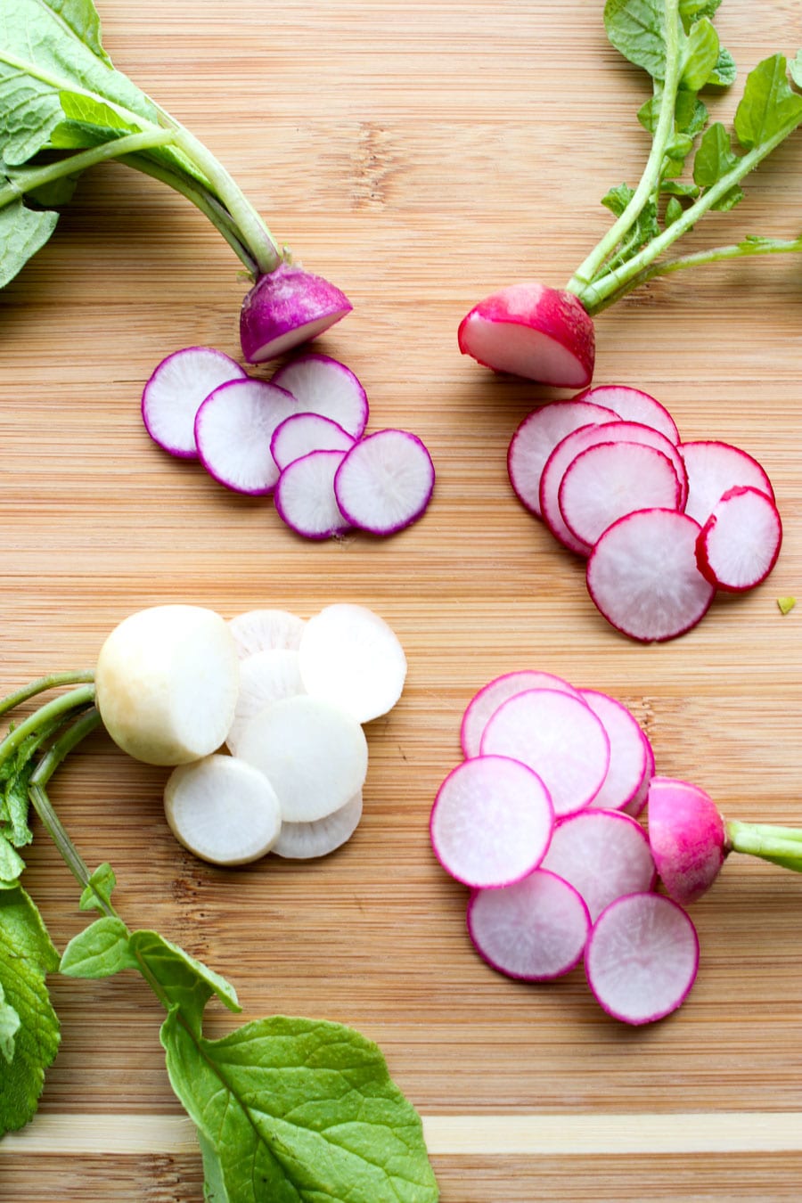 Easter radishes on a cutting board. Their colors are pink, purple, white, red