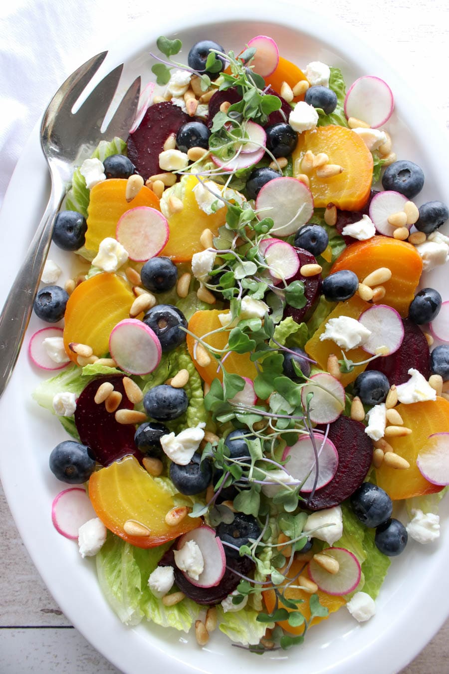 Large white platter with roasted beet salad with goat cheese