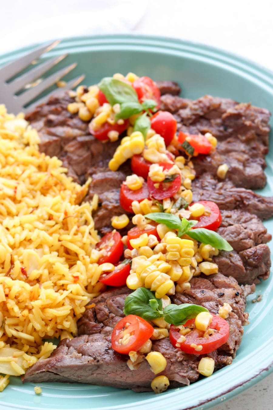 Platter of skirt steak with tomato corn salsa and a side of yellow rice