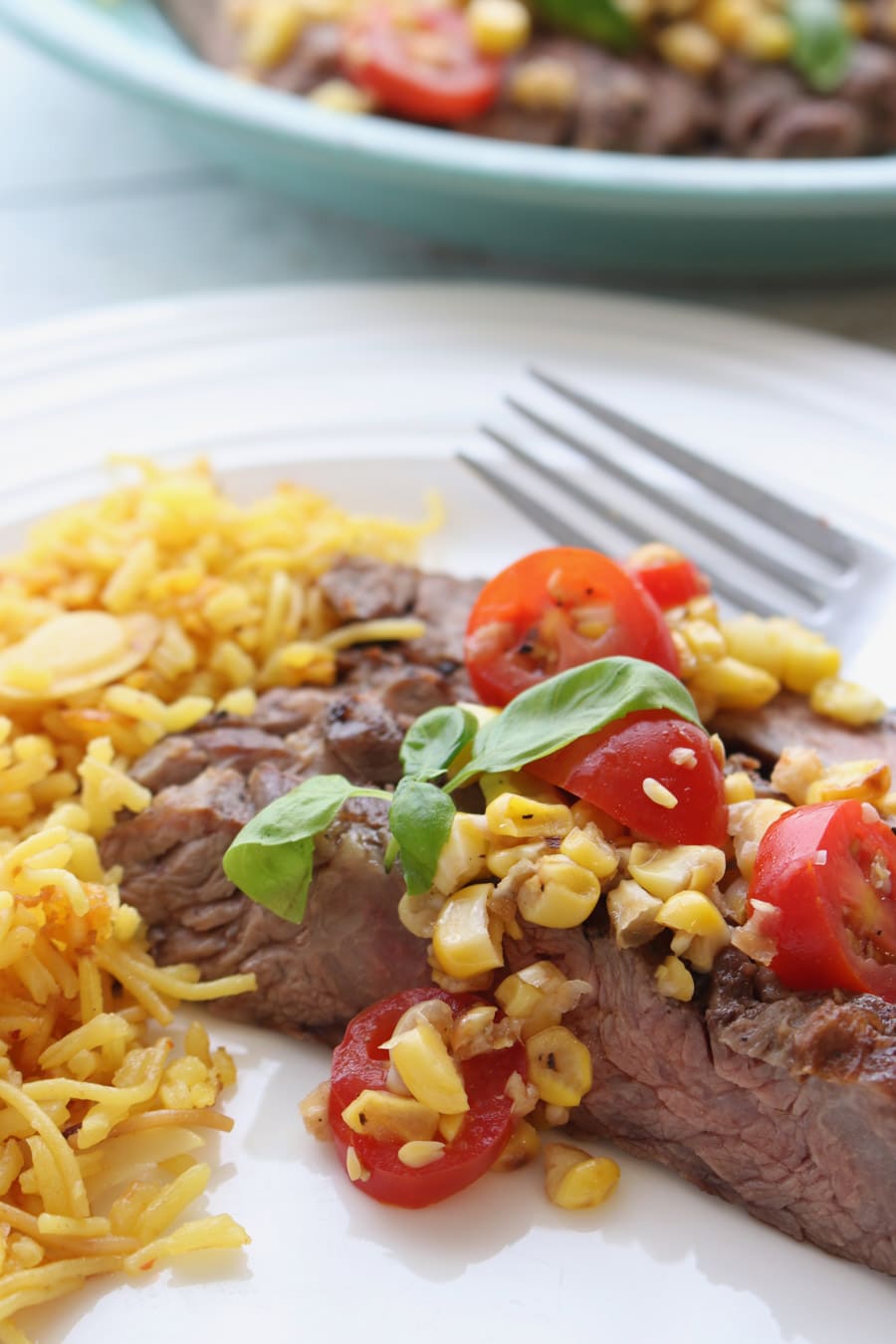 1 serving of skirt steak with tomato corn salsa on a white plate