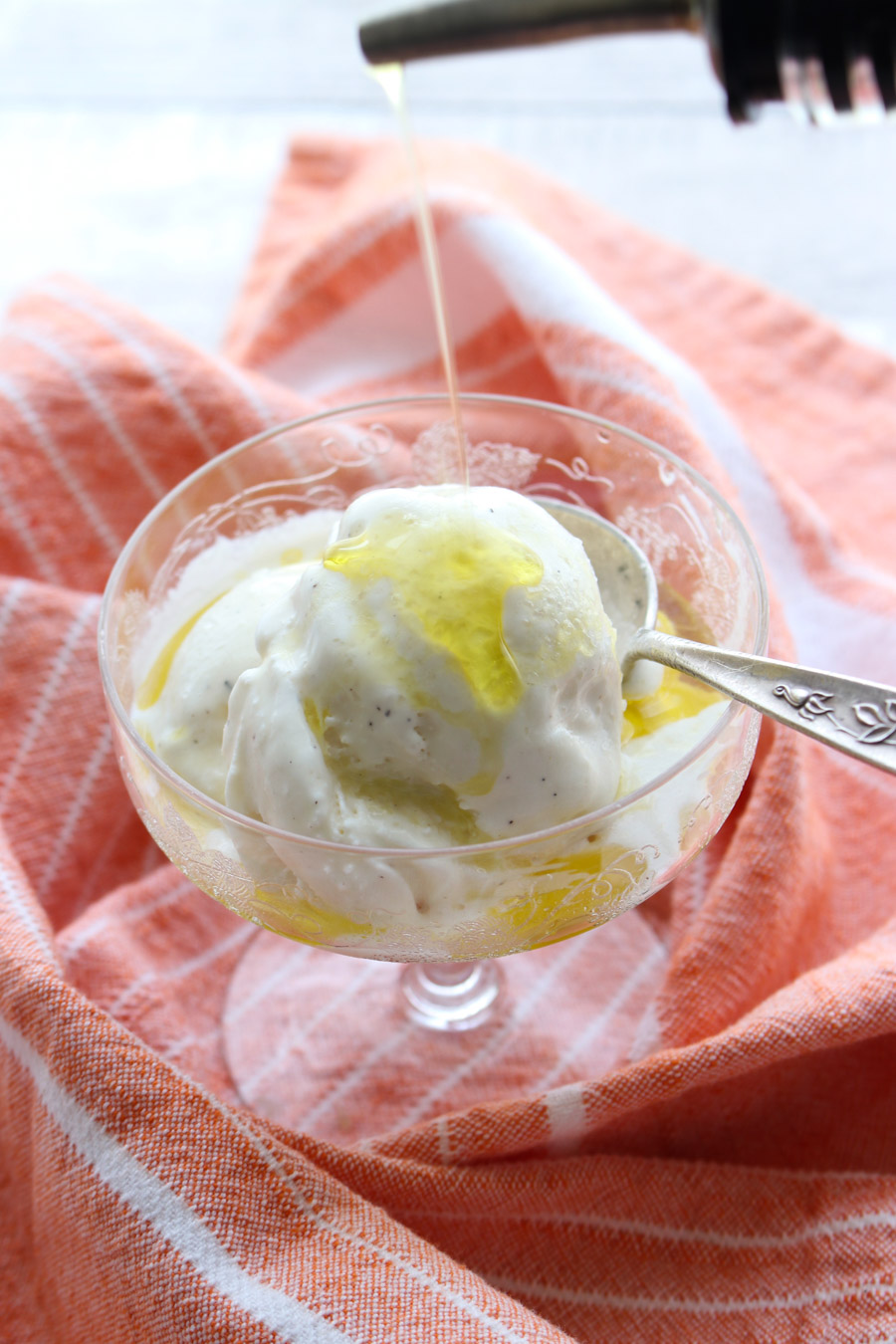 Dish of ice cream with olive oil being poured on it.