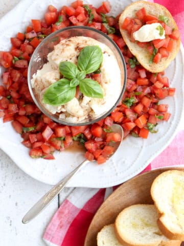 A plate of bruschetta with a bowl of fresh mozzarella in the center and toast on the side