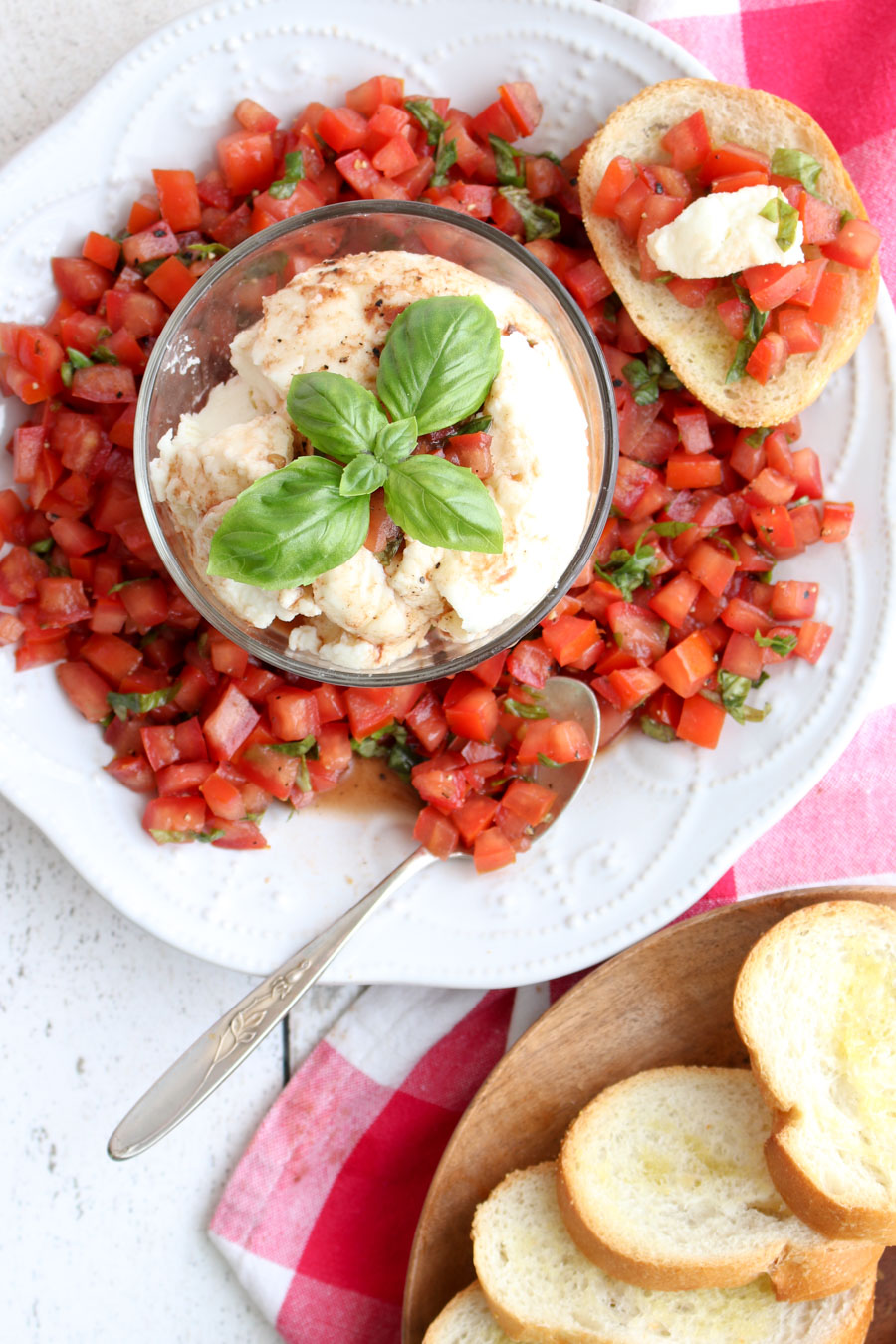 A plate of bruschetta with a bowl of fresh mozzarella in the center and toast on the side