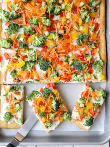 Veggie pizza on a sheet pan with three square pieces cut out