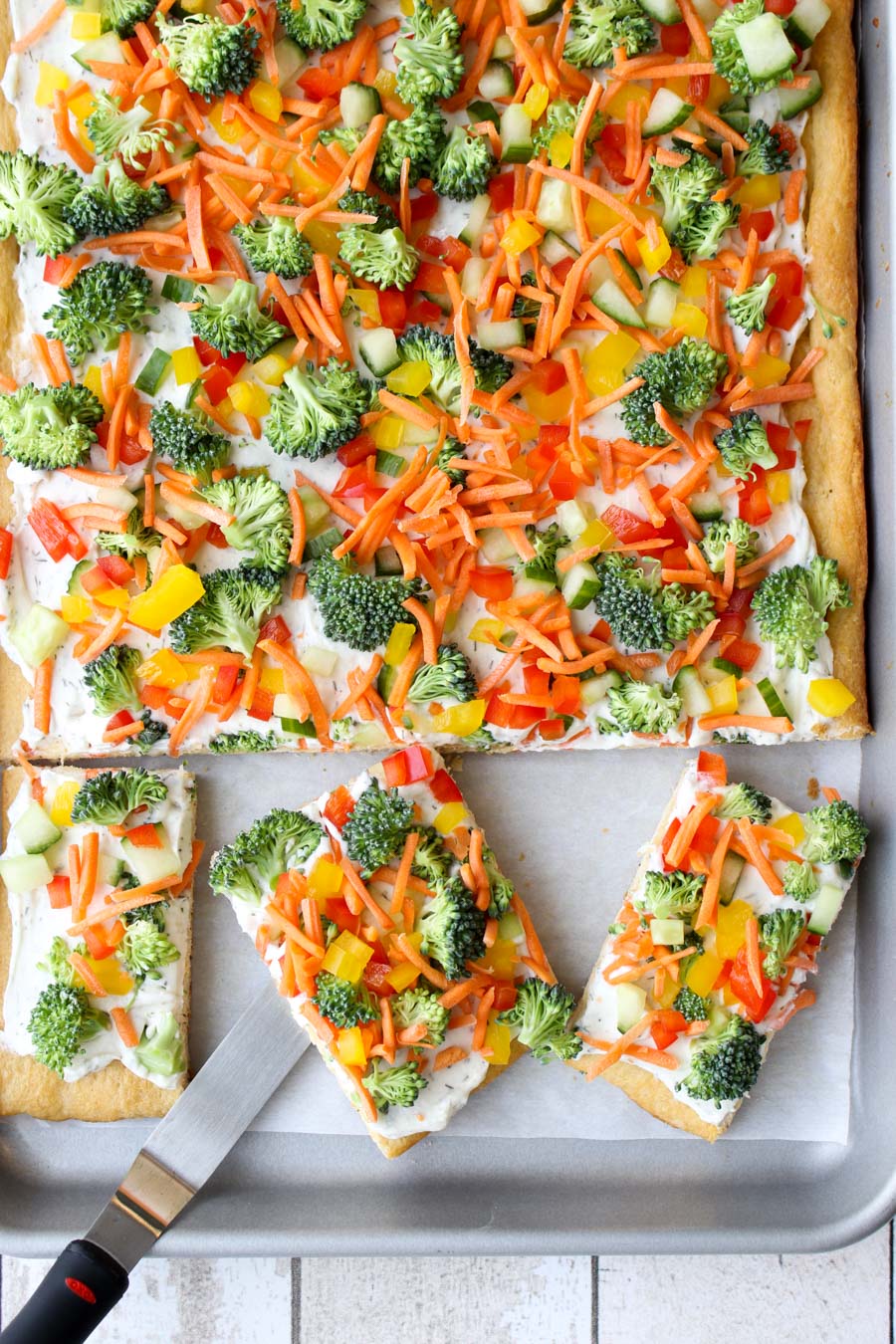 Veggie pizza on a sheet pan with three square pieces cut out