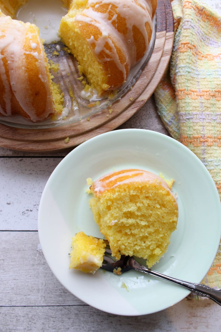 looking down at a slice of lemon cake and a small part of the whole cake