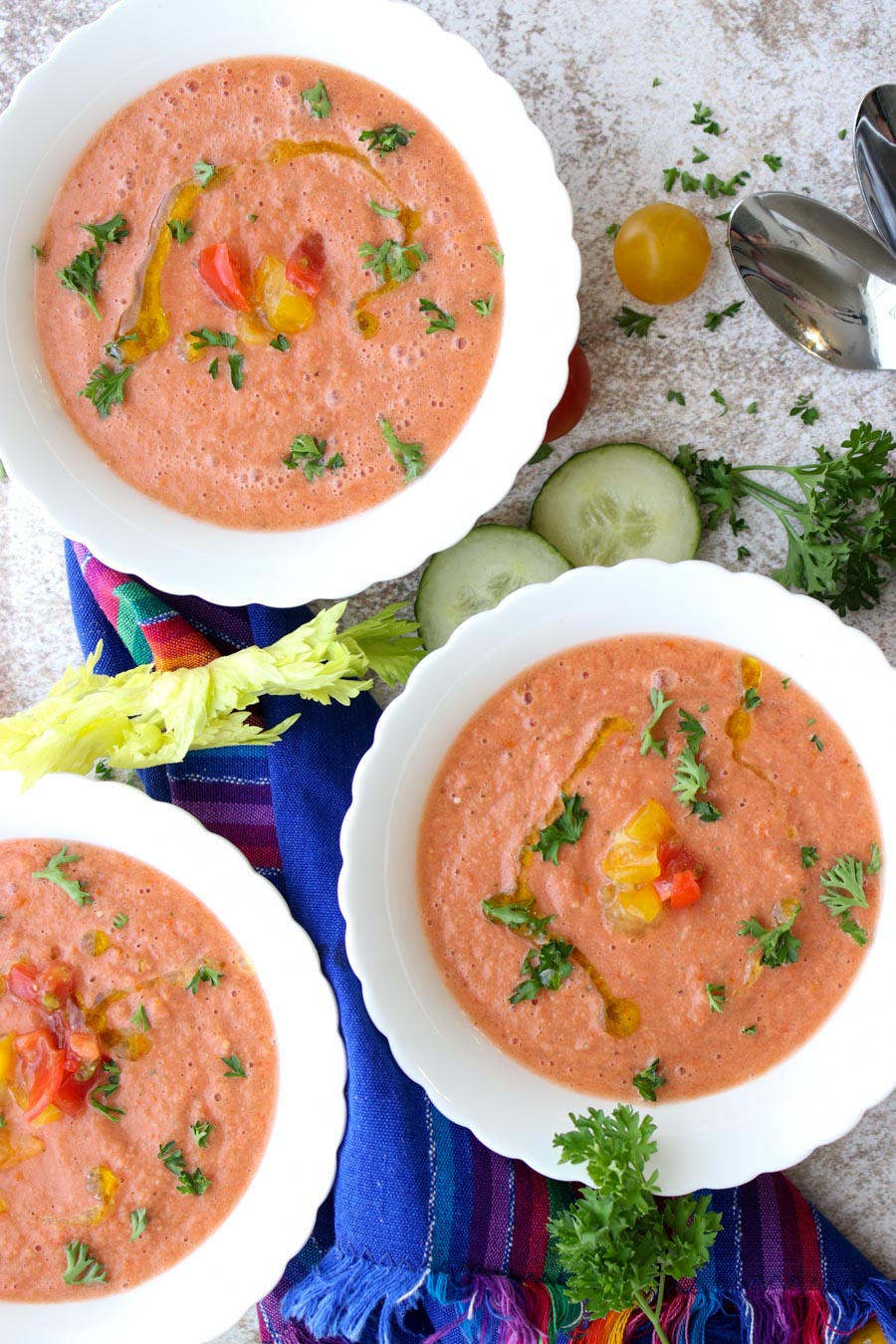 Three bowls of gazpacho topped with tomatoes and parsley 