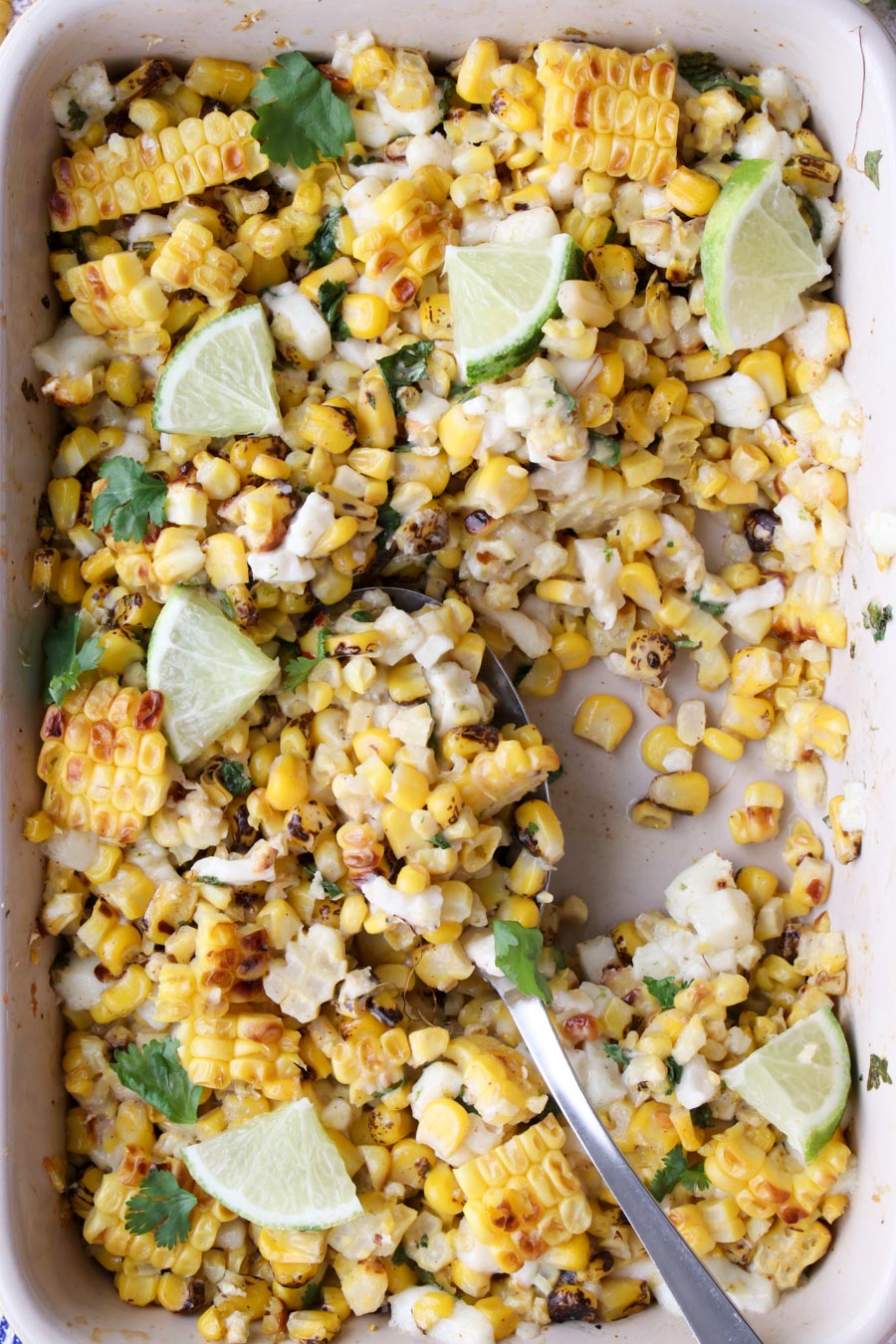 Close up shot of Elote in a casserole dish with a serving spook