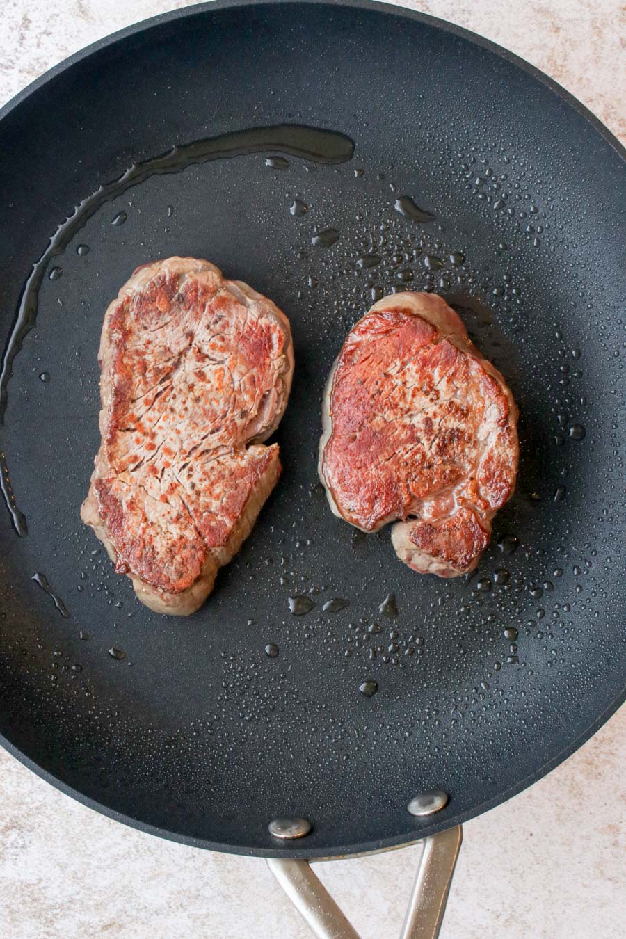 two filet steaks searing in a skillet