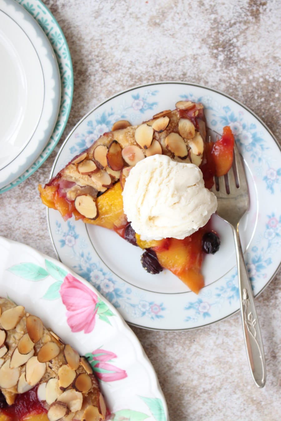 Close up of a piece of pie with ice cream on top sitting on blue flowered plate