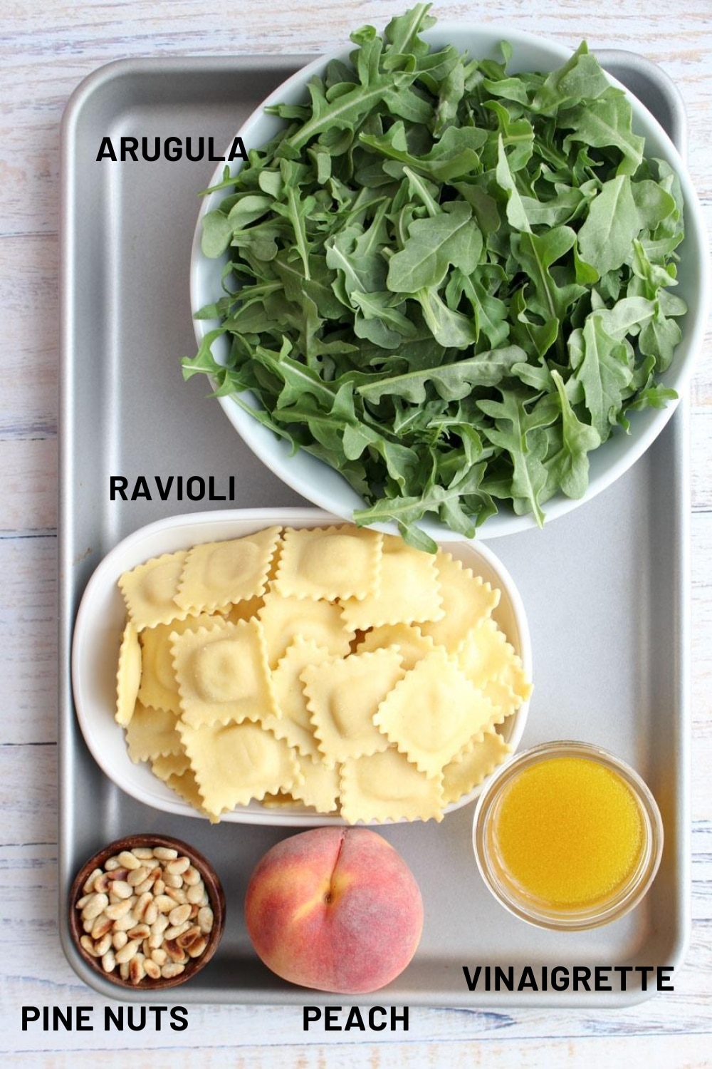 cookie sheet with the ingredients needed to make arugula pasta salad with peaches