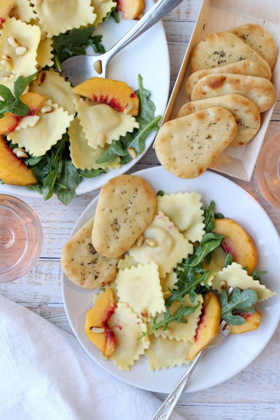 arugula pasta salad on a small plate with pita bread and a glass of rose wine on the side