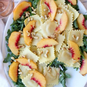 White platter with ravioli, arugula, peaches