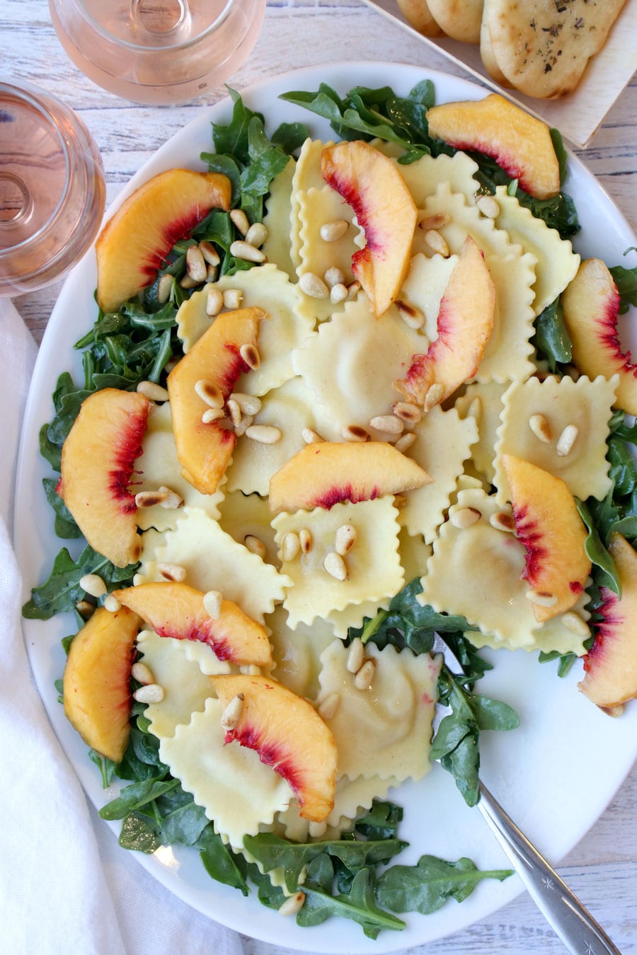 White platter with ravioli, arugula, peaches