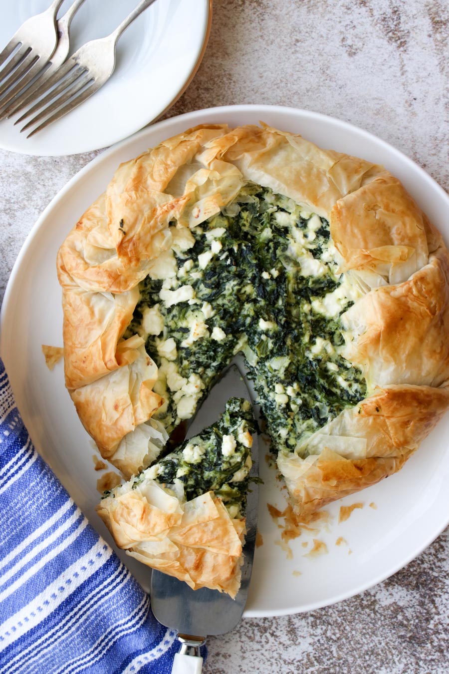 Spinach galette on a white plate with one slice being cut out