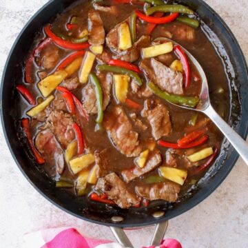 A skillet with cooked pepper steak