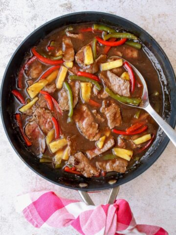 A skillet with cooked pepper steak