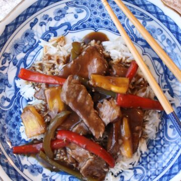 Blue plate with white rice and pepper steak and chop sticks on the side of plate