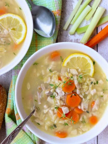 White bowl wit greek chicken soup and a spoon in it