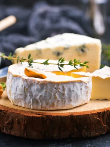 Brie Cheese wheel on a board with sprig of thyme on top