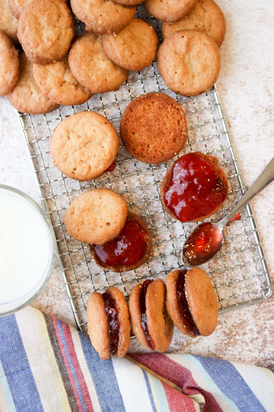 Peanut butter cookies on a cookie rack with strawberry jelly