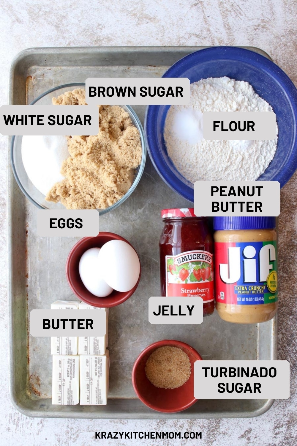 Cookie sheet with all of the ingredients needed to make peanut butter and jelly cookies